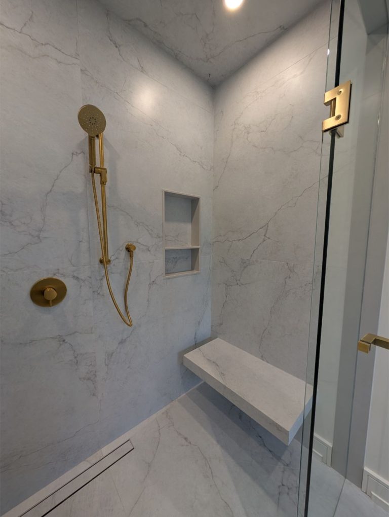 posh glass shower with marble walls and gold fixtures